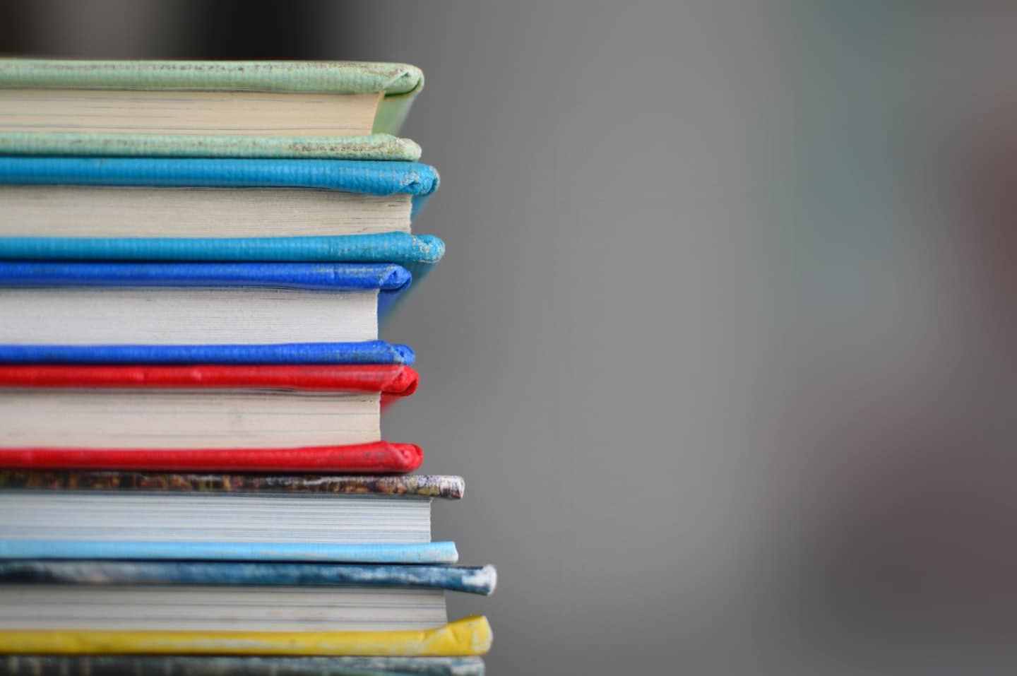 Ein Stapel bunter Bücher vor dunklem Hintergrund mit der Einladung, sich für den psychologischen Lerntyp-Test anzumelden.